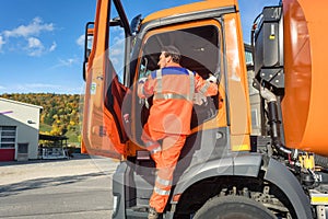 Garbage removal worker getting into the disposal vehicle