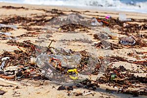 Garbage on sea beach, unsorted rubbish, plastic, glass bottle, metal can, trash, refuse, litter, environmental pollution, ecology