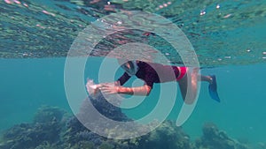 garbage in the sea. Volunteer, girl teenager, in snorkeling mask, collects floating rubbish over the coral reef