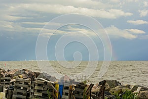 Garbage on the shore of the pond of the sea on the horizon city and rainbow