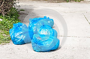 Garbage on the urban street in blue plastic bags polluting the city with junk and litter