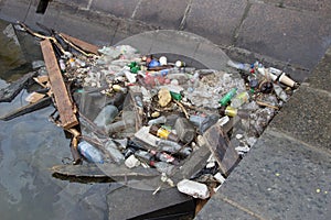 Garbage in the water, plastic pollution, waste on the river bank.