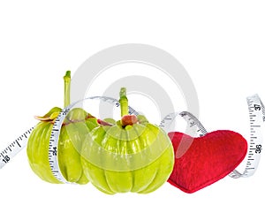 Garcinia cambogia fresh fruit with red heart and measuring tape, isolated on white. Fruit for diet and good health.