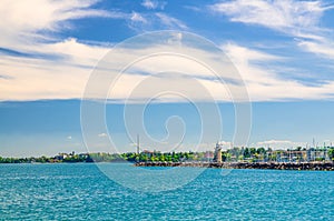 Garda Lake azure turquoise water surface with view of lighthouse on stone pier mole
