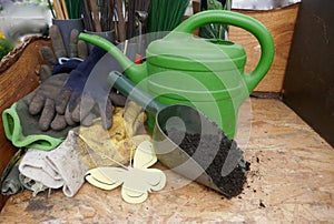 Garden accessories, watering can, hand scoop and protective gloves on rustic wooden background. Close-up.