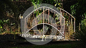 Garden with arch-shaped iron bridge and water fountain