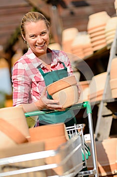 Garden center woman putting clay pots cart
