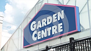 garden centre sign on front of building top with black fence below, blue white