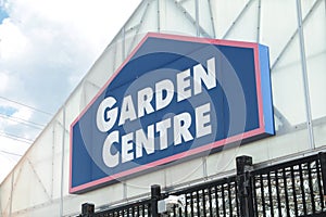 garden centre sign on front of building top with black fence below, blue white. p