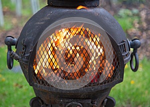 A garden chiminea fire blazing with smoke and flames