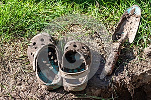 Garden clogs and shovel standing on the mud
