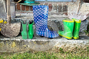 Garden equipment - rubber boots, schovels and srtaw hats in sunny day