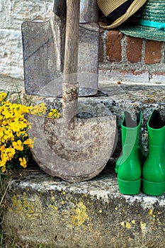 Garden equipment - rubber boots, schovels and srtaw hats in sunny day