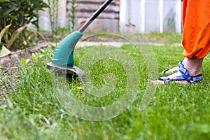 Garden equipment. Woman mowing the grass with a trimmer.