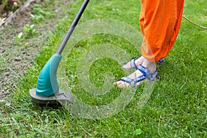 Garden equipment. Woman mowing the grass with a trimmer.