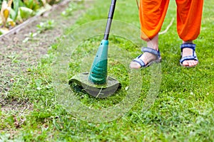 Garden equipment. Young woman mowing the grass with a trimmer.