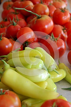 Garden fresh red tomatoes and yellow banana peppers are stacked and waiting to be canned