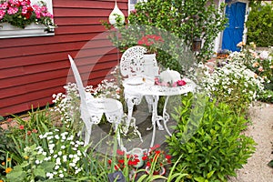 Garden furniture set with flowers in front of country house.