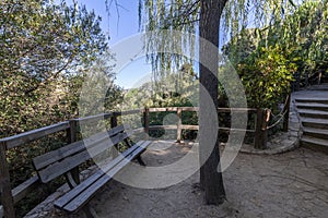 A garden with a gazebo with a wooden railing and a bench made of the same material