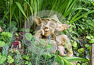 Garden gnome with impish smile thinking - Clay dwarf in garden