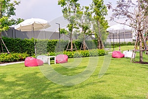 Garden of green grass lawn, white and pink beanbag under white umbrella
