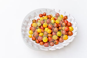 Garden harvest of yellow and red cherry tomatoes on white tray