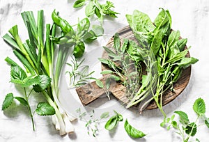 Garden herbs - spinach, basil, thyme, rosemary, sage, mint, onion, garlic on a light background, top view. Fresh food ingredients