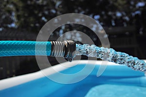 Garden hose pouring water into an inflatable pool