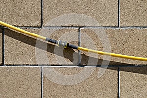 The garden hose with the repair coupling hangs on a wall from smooth stone blocks. Background, texture series