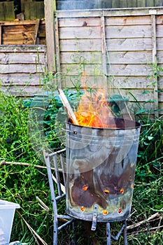 A garden incinerator bin rested on a metal chair frame burning scrap wood