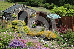 Garden in Ireland in summertime featuring rockery, forge building and patio with seating area