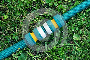 Garden irrigation hoses connected with a modern plastic hose connector for quick connection lying on the grass close up