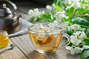 Garden jasmine flowers, healthy herbal tea cup, honey jar and vintage copper tea kettle