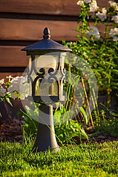 Garden lamp, made in the Middle Ages, on a lawn with a juicy green grass