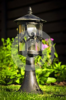 Garden lamp, made in the Middle Ages, on a lawn with a juicy green grass
