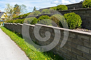 Garden landscape design. Decorative wall made of dark gray stone blocks or concrete cement bricks. Garden decorative trimmed