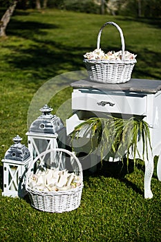 Garden party decorations: basket of flowers and petals, lantern with candles, vintage table