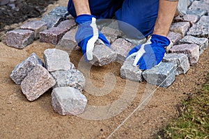 Garden path construction - worker laying granite stone pavers