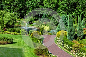 Garden path leading to a pond with a fountain and landscape design.