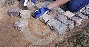 Garden path pavement - worker laying granite cobblestone