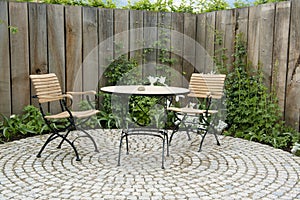 Garden patio with round table and two chairs. Outdoor furniture made of iron and wood material photo