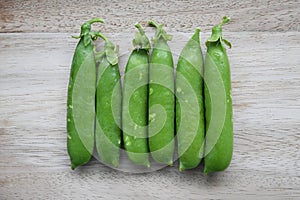 Garden pea pods (Pisum sativum), isolated on a wood background