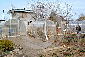 Garden plot with greenhouses and dug-up beds in spring