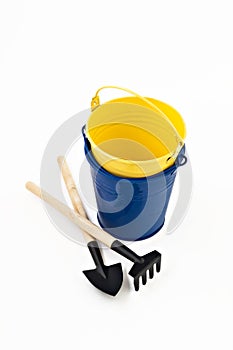 Garden shovel, rake and blue metal bucket isolated