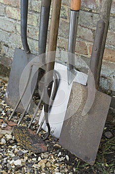 Garden Shovels And Tools Leaning On Brick Wall