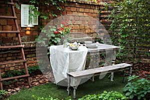 Garden in summer with patio, wooden garden furniture and barbecue. Dining table in backyard at home. Cozy space in patio or balcon