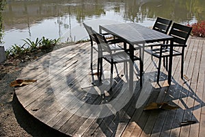 Garden table and chairs on a deck by a river in summer