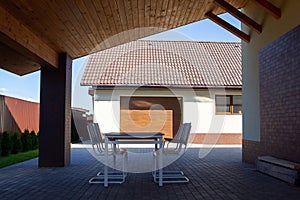 Garden table, chairs stand under a canopy in the shade. Hot sunny day