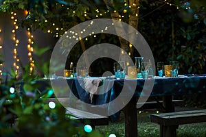 garden tables with cloth, glassware illumined by fairy lights