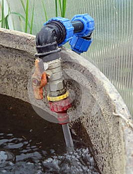 Garden tool. Water from the tap pours into the barrel